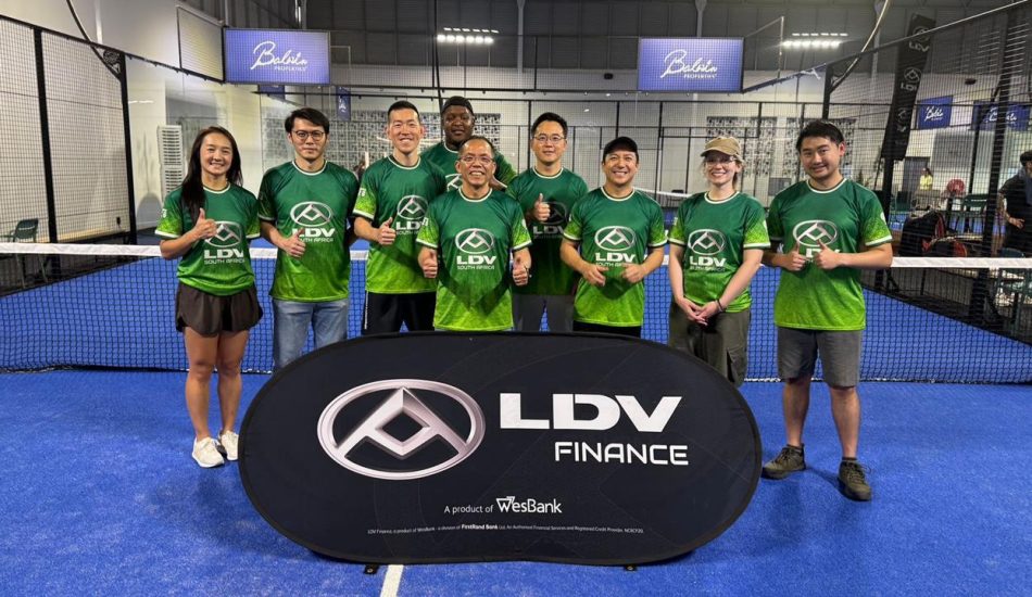 Group of ten people in green LDV Finance shirts posing for a team photo on a blue indoor court behind a large LDV Finance banner.